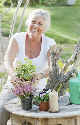 Ältere Frau arrangiert Blumen im Freien, lizenzfreies Stockfoto