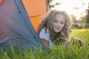 Teenage girl laying in tent at campsite - CUF39192