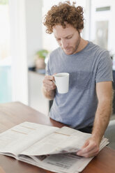 Man reading newspaper at breakfast - CUF39195