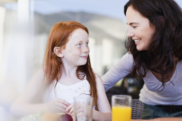 Mother smiling at daughter at breakfast - CUF39264