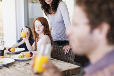 Mädchen beobachtet Vater beim Trinken von Orangensaft - CUF39266
