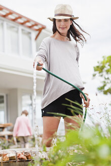 Woman watering plants in backyard - CUF39274