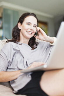 Frau am Mobiltelefon mit Laptop - CUF39278