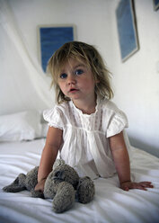 Girl holding teddy bear on bed - CUF39308