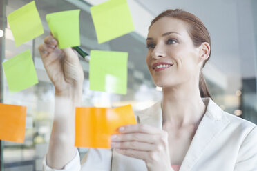 Businesswoman brainstorming using sticky notes - CUF39365