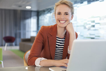 Businesswoman sitting at desk, using laptop - CUF39369