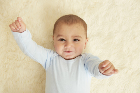 Baby auf Schafsfell-Teppich liegend, lizenzfreies Stockfoto