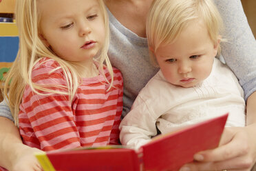 Mutter liest Bilderbuch mit zwei Töchtern - CUF39397