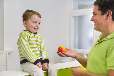 Mann gibt kleinem Jungen Apfel - CUF39447