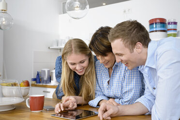 Jugendliche Großmutter betrachtet digitales Tablet mit erwachsenen Enkelkindern - CUF39472