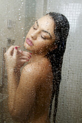 Junge Frau mit geschlossenen Augen genießt eine Dusche - CUF39476