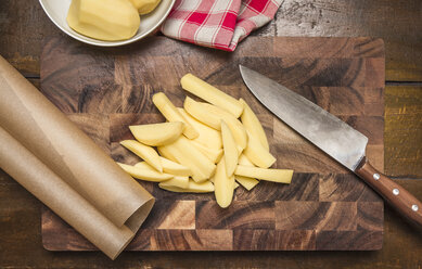 Still life of peeled and sliced potatoes, kitchen knife on chopping board - CUF39523