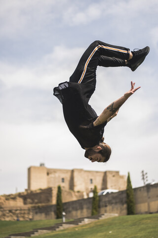 Spanien, Lleida, tätowierter Mann macht Parkour in einem Park, lizenzfreies Stockfoto