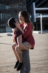 Young man lifting up happy girlfriend on city square - MAUF01456