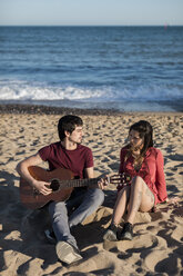 Paar mit einer Gitarre am Strand sitzend - MAUF01459