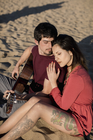 Verliebtes Paar mit Gitarre am Strand, lizenzfreies Stockfoto