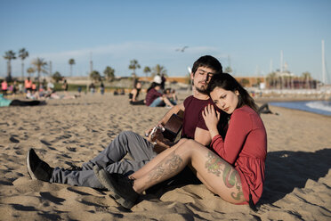 Spanien, Barcelona, Paar mit Gitarre am Strand sitzend - MAUF01462