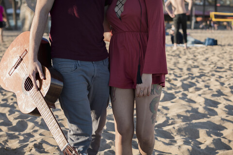 Spanien, Barcelona, Nahaufnahme eines verliebten Paares mit einer Gitarre am Strand, lizenzfreies Stockfoto