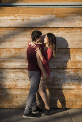 Affectionate young couple hugging at wooden wall - MAUF01474