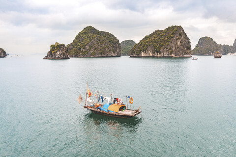 Vietnam, Ha Long Bucht, mit Kalksteininseln und kleinem Boot, lizenzfreies Stockfoto