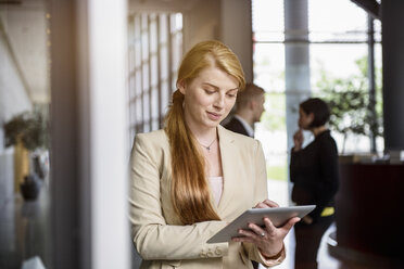 Young woman using touchscreen on digital tablet in office - ISF16537