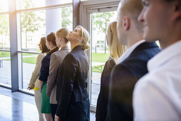 Geschäftsfrauen und -männer warten in einer Reihe im Büro - ISF16553