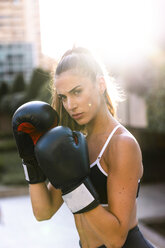 Portrait of sportive young woman boxing in the city - KKAF01157