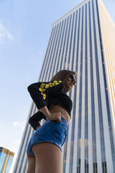 Attractive young woman standing in front of skyscraper in the city - KKAF01182