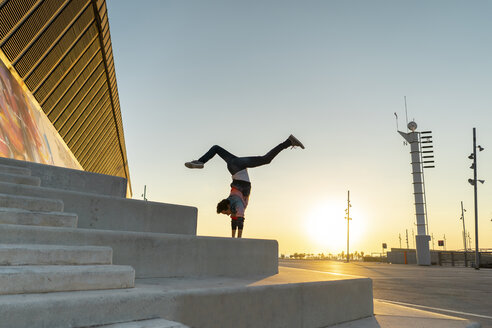 Akrobat im Handstand auf einer Treppe bei Sonnenaufgang - AFVF00664