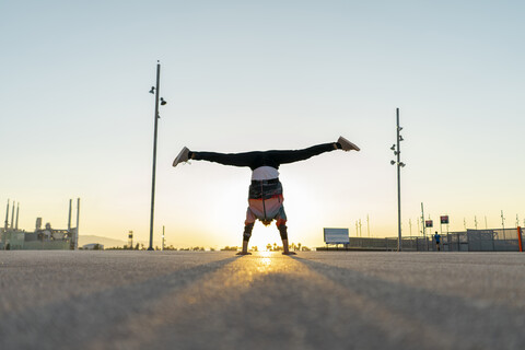 Acrobat doing handstand in the city at sunrise stock photo
