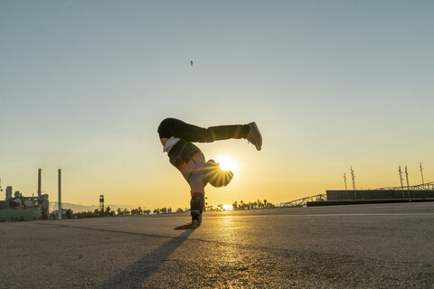 Akrobat beim Handstand in der Stadt bei Sonnenaufgang, lizenzfreies Stockfoto