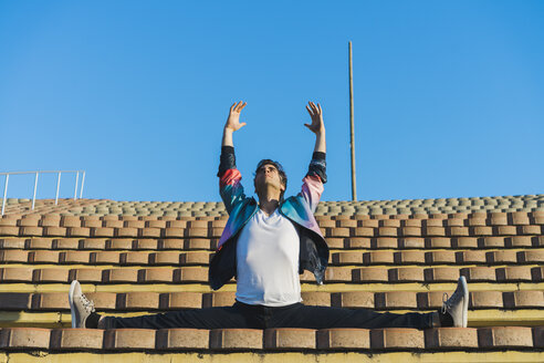 Mann macht Seitwärtsspagat auf der Treppe eines Stadions - AFVF00682
