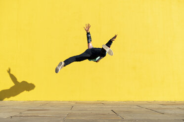 Acrobat jumping somersaults in front of yellow wall - AFVF00696