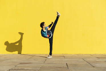Akrobat beim Bewegungstraining vor einer gelben Wand - AFVF00697
