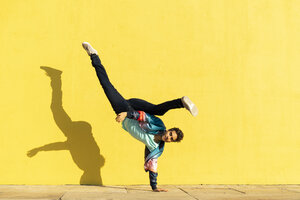 Akrobat beim Bewegungstraining vor einer gelben Wand - AFVF00698