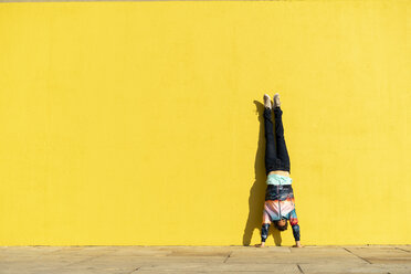 Acrobat doing handstand in front of a yellow wall - AFVF00700