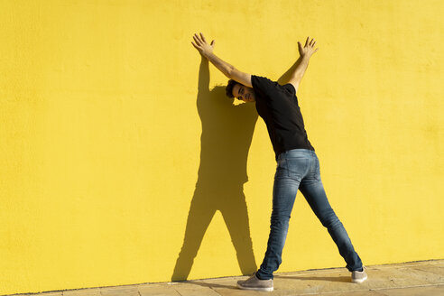Mann stehend mit Händen an gelber Wand, Rückansicht - AFVF00706