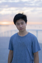 Young Chinese man at beach at sunrise, portrait - AFVF00712