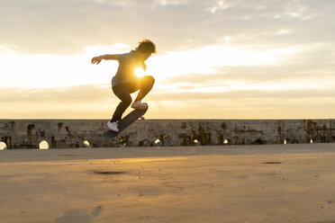 Junger chinesischer Mann auf dem Skateboard bei Sonnenaufgang am Strand - AFVF00732