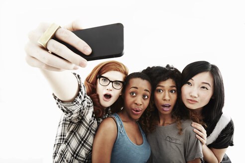 Studio-Porträt von vier jungen Frauen, die ein Selfie mit ihrem Smartphone machen - ISF16654