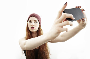 Studio-Porträt einer jungen Frau, die ein Selfie mit ihrem Smartphone macht - ISF16666
