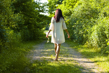 Rückansicht einer jungen Frau, die barfuß auf einem Feldweg spazieren geht, Delaware Canal State Park, New Hope, Pennsylvania, USA - ISF16673