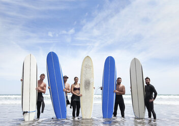 Gruppenbild von männlichen und weiblichen Surferfreunden, die mit Surfbrettern im Meer stehen - ISF16755