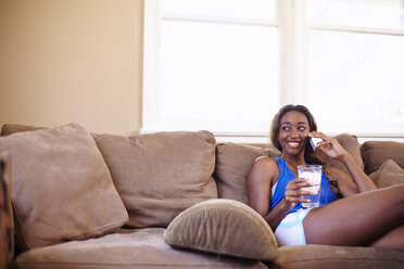 Young woman on a training break, chatting on smartphone in sitting room - ISF16780