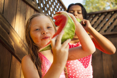 Zwei Mädchen essen Scheiben von Wassermelone im Garten - ISF16784