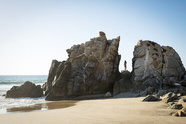 Junge Frau steht auf Felsen am Strand - ISF16798