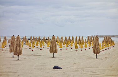 Rows of folded beach umbrellas on beach, Pescara, Abruzzo, Italy - ISF16801