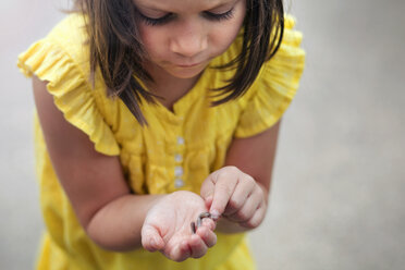 Girl holding and looking down at worm - ISF16882