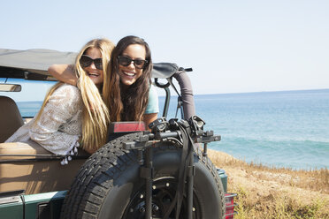 Porträt von zwei jungen Frauen, die sich aus einem Jeep an der Küste lehnen, Malibu, Kalifornien, USA - ISF16934