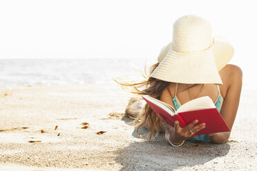 Junge Frau, die am Strand ein Sonnenbad nimmt und ein Buch liest, Malibu, Kalifornien, USA - ISF16948